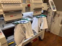 an embroidery machine with white shirts on it