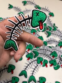 a person holding a fish skeleton embroidered patch